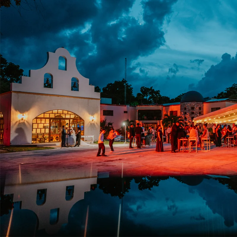 Hacienda-style wedding venue reflected in a pool at dusk