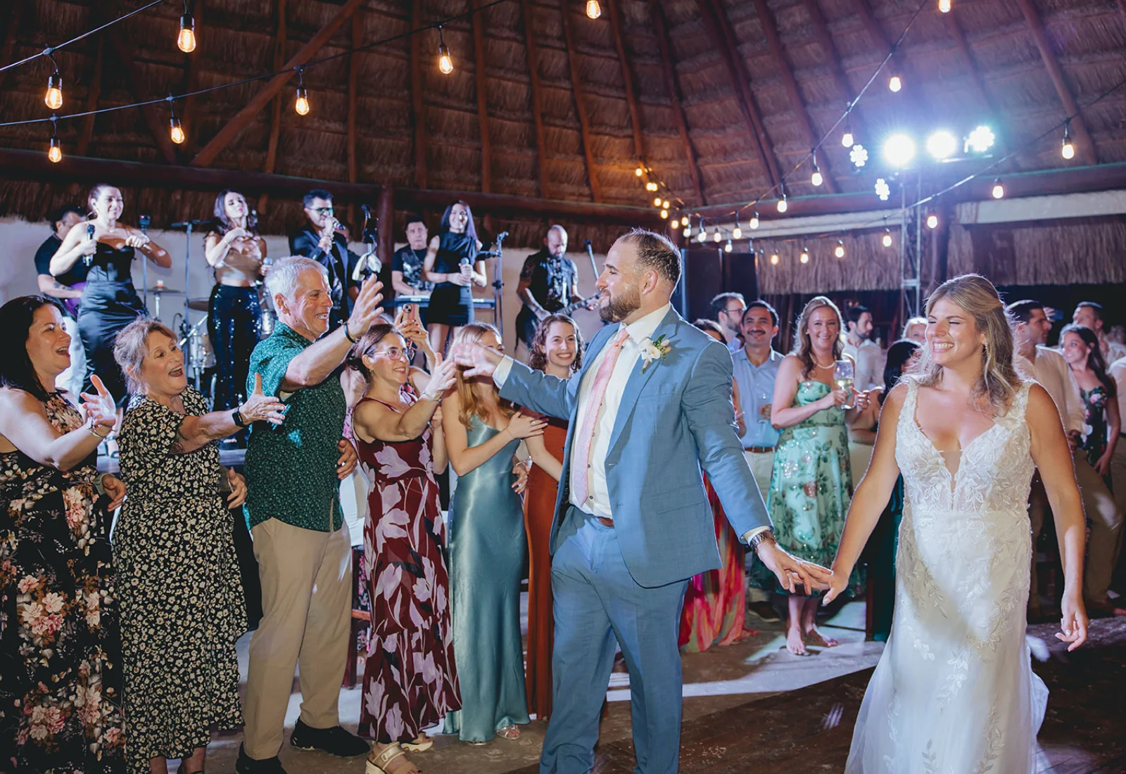 Guests and the newlyweds dancing with a live band at a Cancun wedding reception