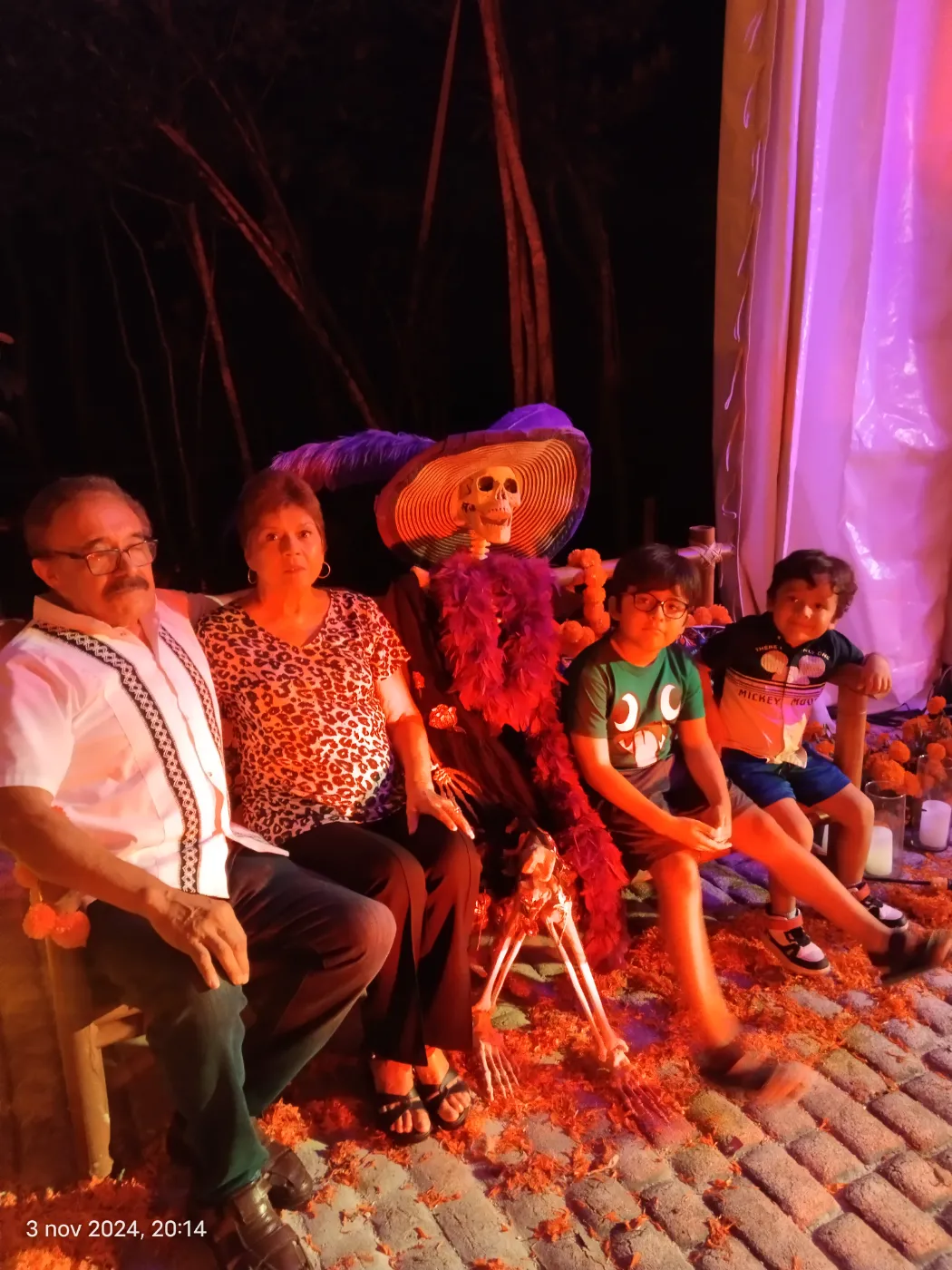 Family seated with a Catrina figure surrounded by marigolds